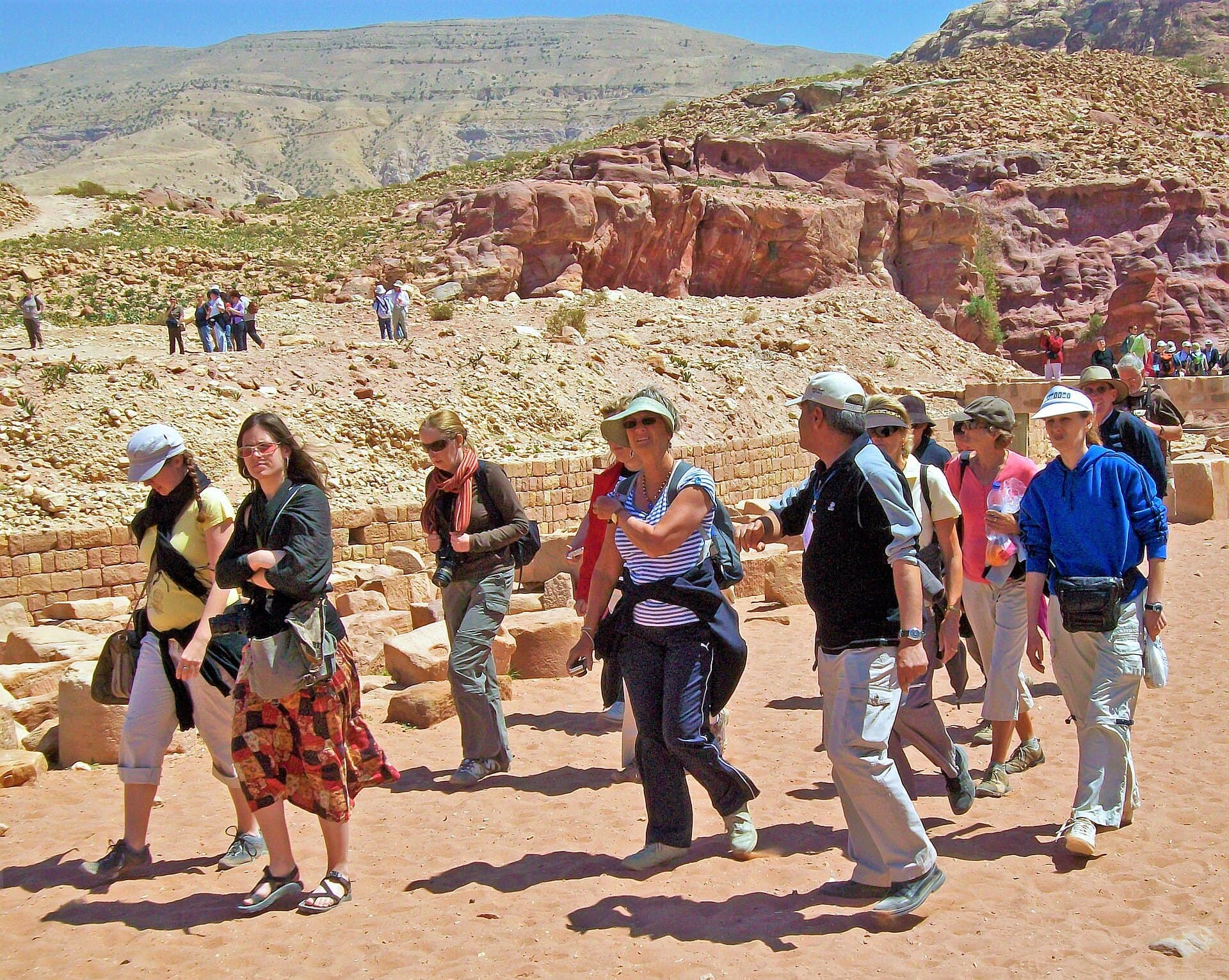 Petra'da bir kanyon patikasında rehberiyle yürüyen gezgin grubu